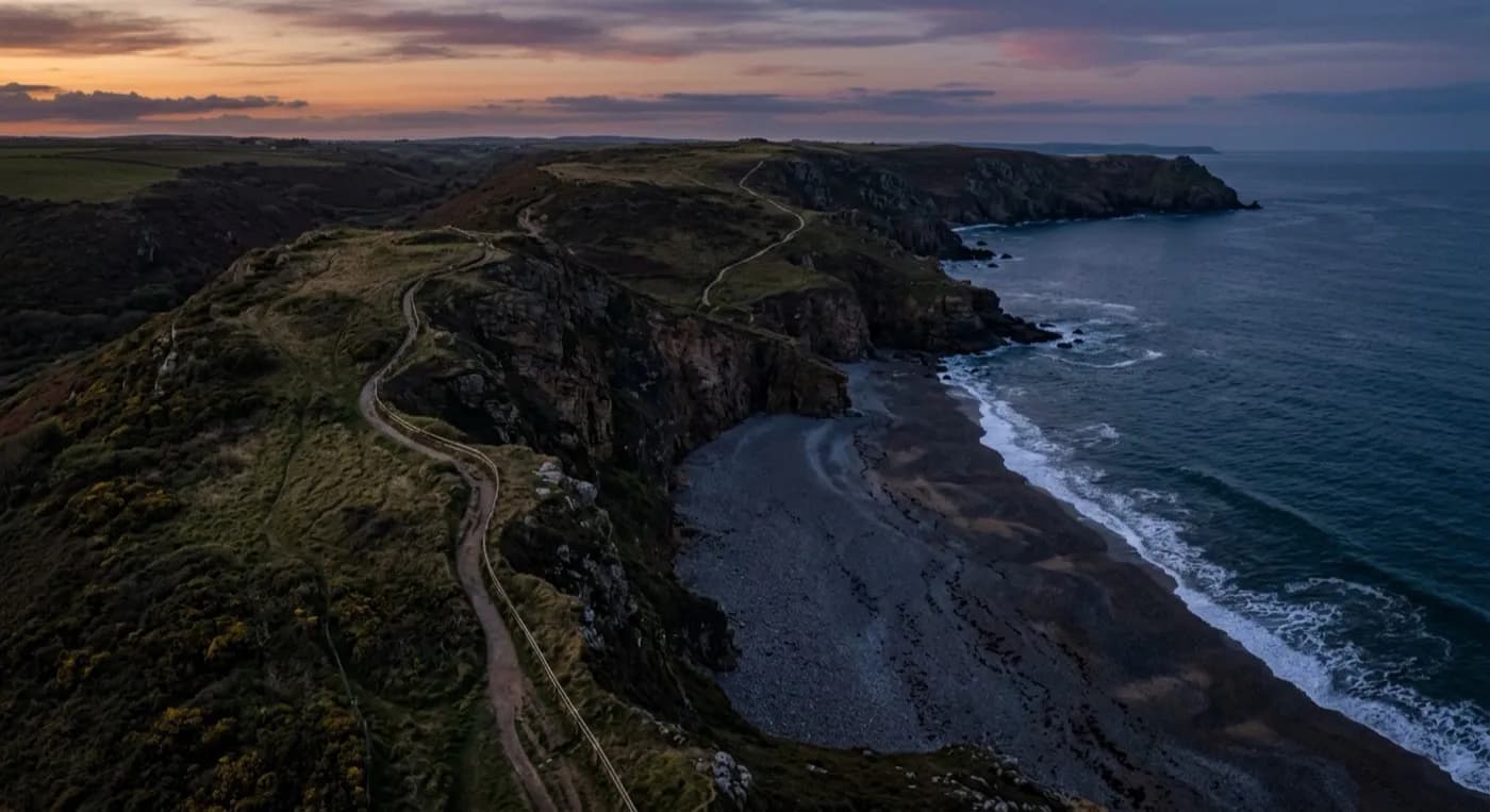 Aerial view of the South West coast path along cliffs and a shingle beach at low light